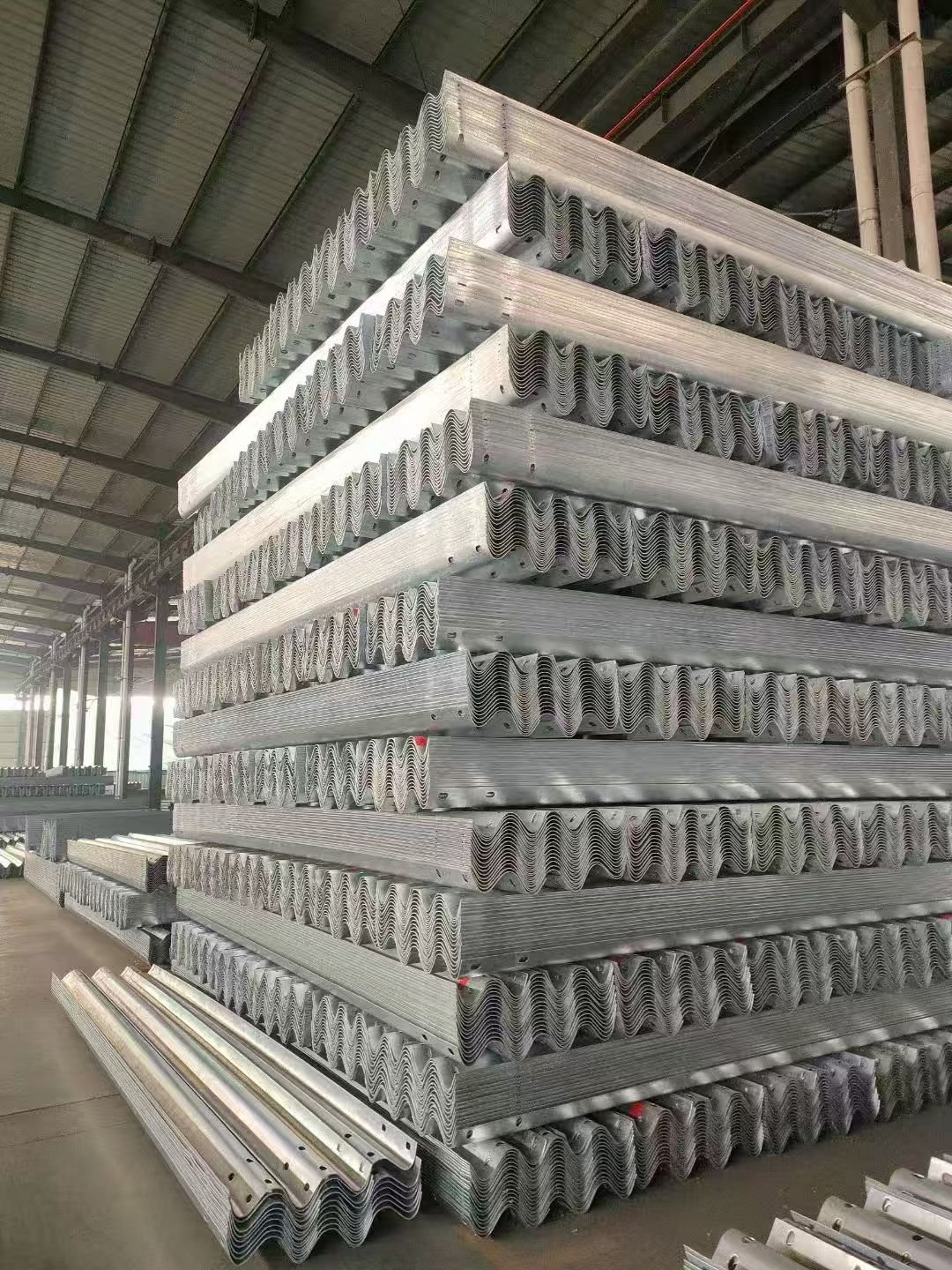 Stacks of silver corrugated guardrail beams