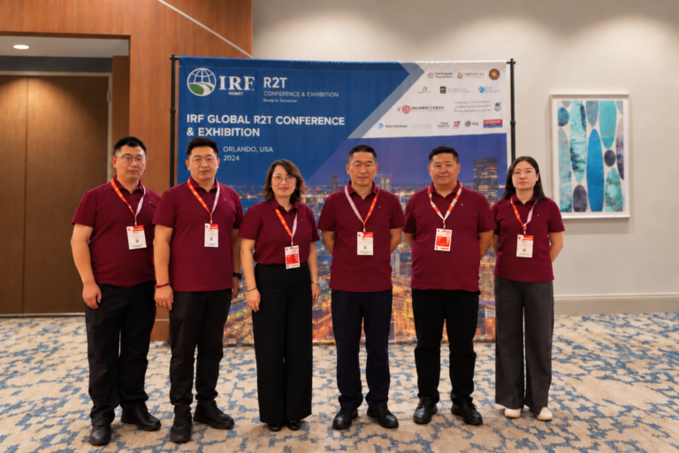 Six people in burgundy shirts composited in front of an IRF R2T conference backdrop.